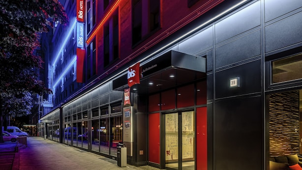 Fachada moderna de hotel con amplios ventanales de vidrio, una llamativa combinación de colores rojo y negro, y el número de habitación '39' a la vista.