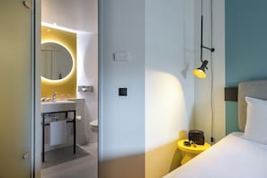 A modern hotel room with a bathroom, a bedside table with a lamp, and a bed. - ibis Berlin Kurfürstendamm (Berlin)