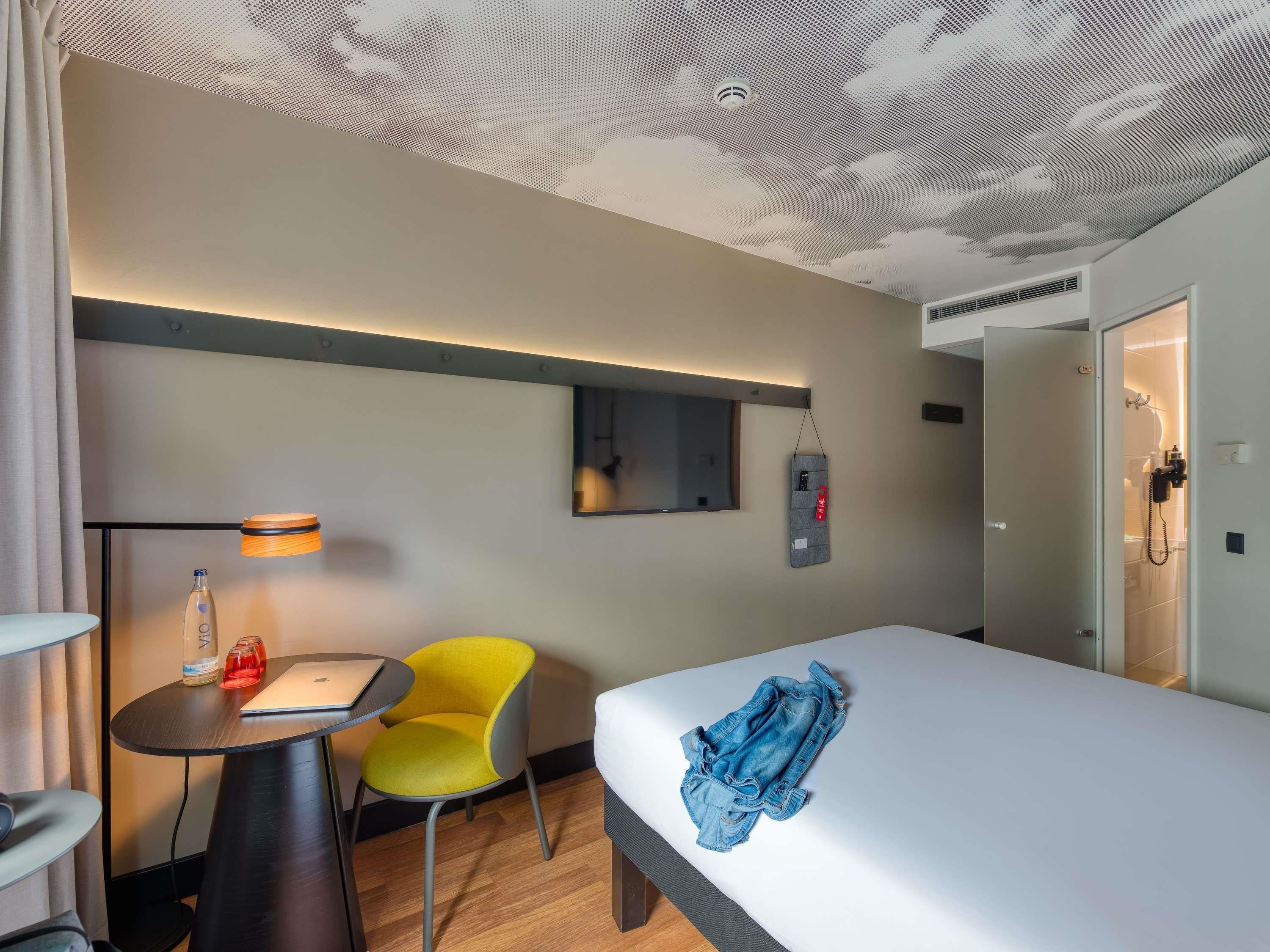 Ein Hotelzimmer mit Bett, Schreibtisch, Stuhl, Lampe und einer Duschkabine.