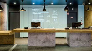 A reception desk with a computer, a clock, and a sign with room types and prices. - ibis Berlin Kurfürstendamm (Berlin)