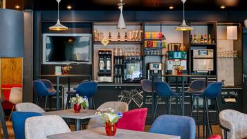A modern bar area with seating, a coffee machine, and a variety of bottles and glasses.