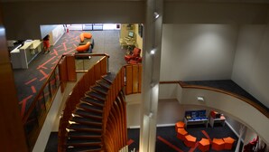 Un interior de varios niveles con una escalera de caracol, zonas de estar y una recepción.