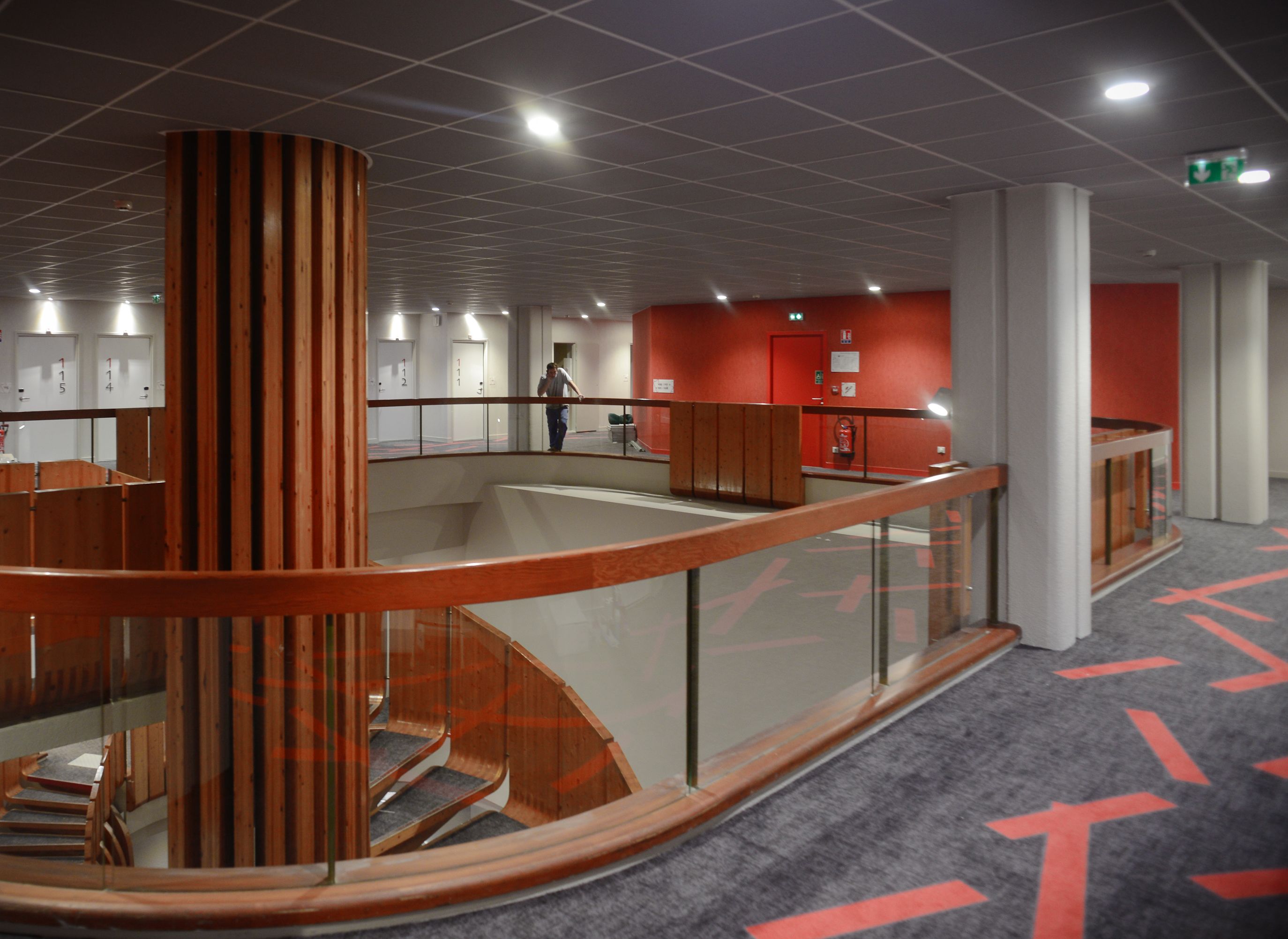 Ein modernes Interieur mit einem zentralen Atrium, einer Treppe und einer roten Akzentwand.