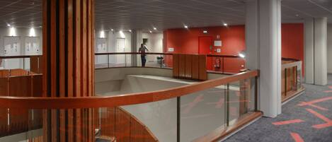 Ein modernes Interieur mit einem zentralen Atrium, einer Treppe und einer roten Akzentwand.