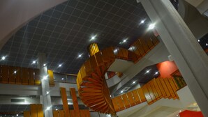 Un interior moderno con una escalera de caracol, iluminación brillante y zonas de estar color naranja.