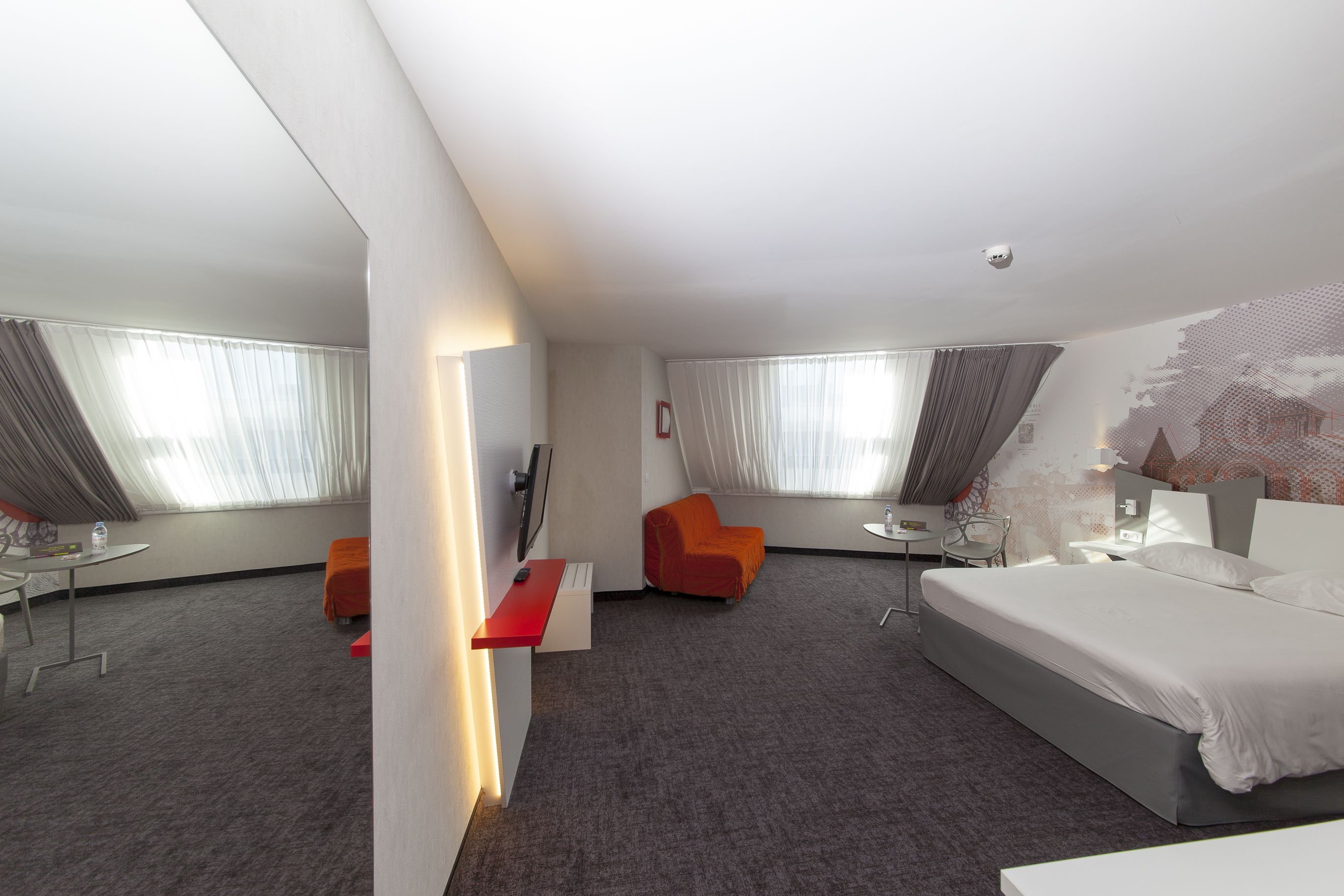 A hotel room with a large bed, a desk, a chair, and a sofa.