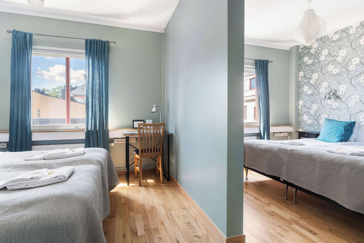 A hotel room with two beds, a desk, and a chair.