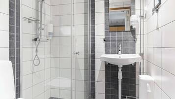 A modern bathroom with a glass-enclosed shower, a white sink, and a toilet.