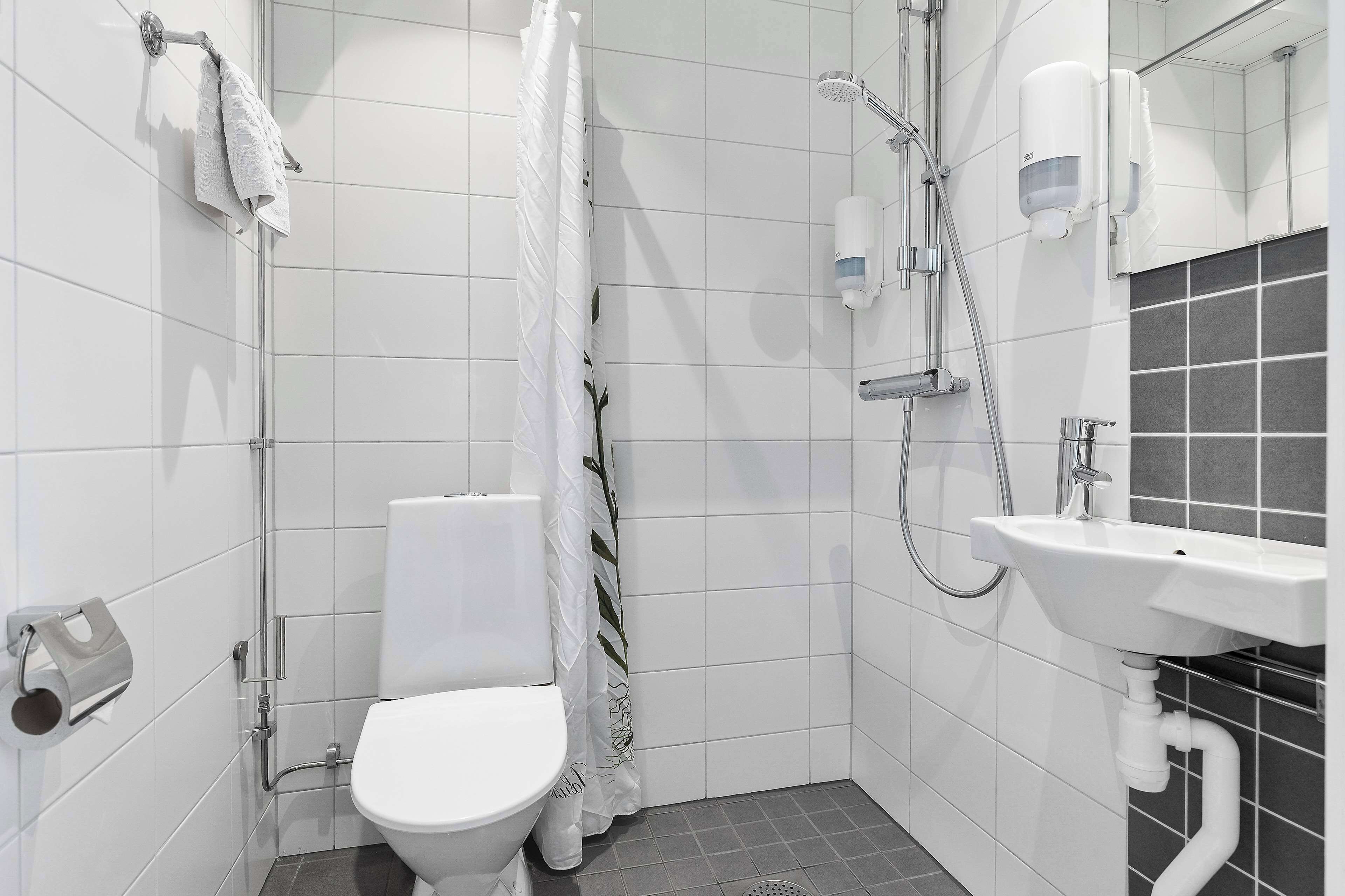 A modern bathroom with a toilet, shower, and sink.