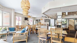 A spacious cafe with wooden furniture, a fruit bar, and a kitchen area. - Best Western Uppsala (Uppsala)