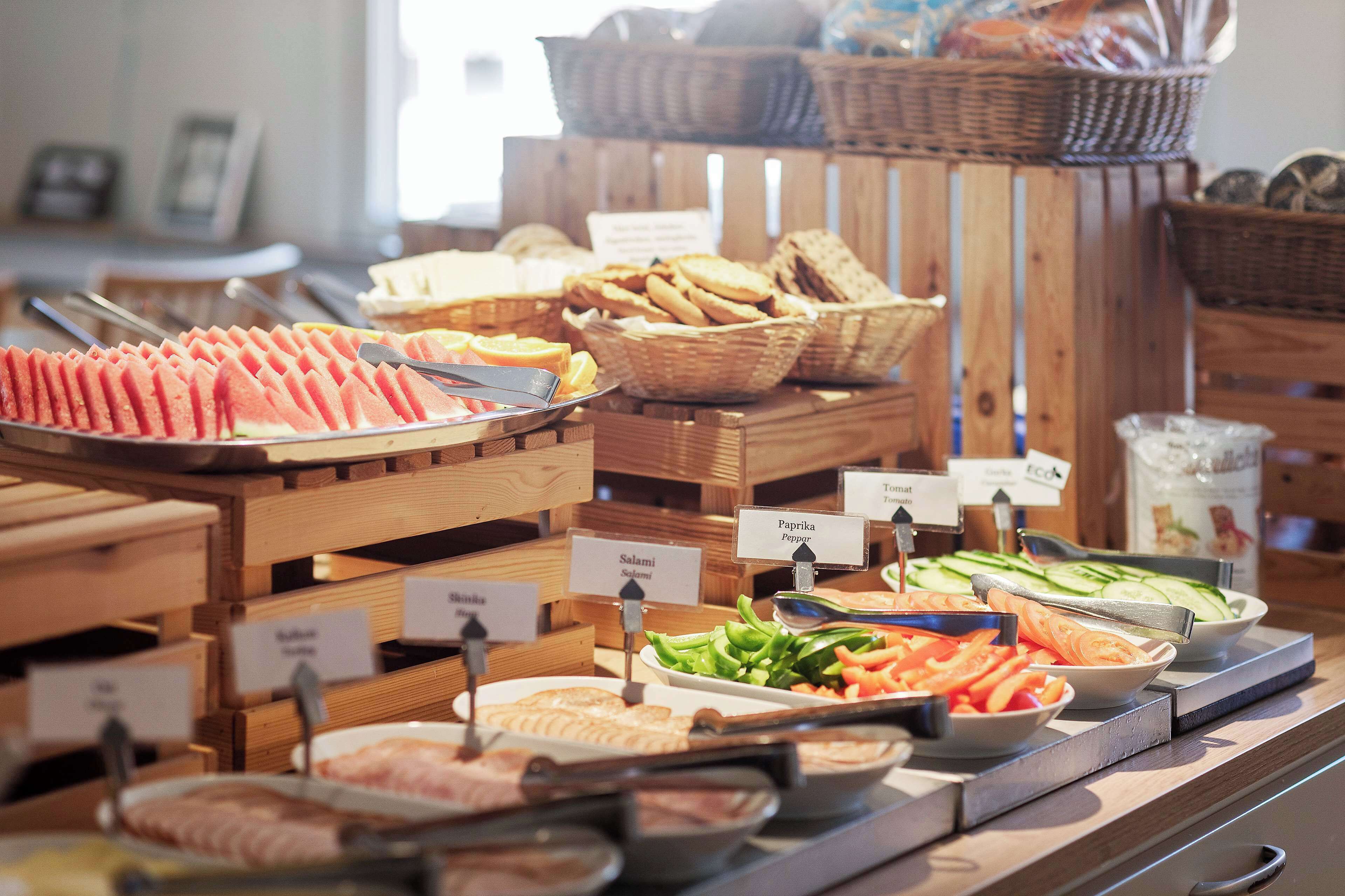 A buffet with various food items including sliced watermelon, bread, and vegetables.