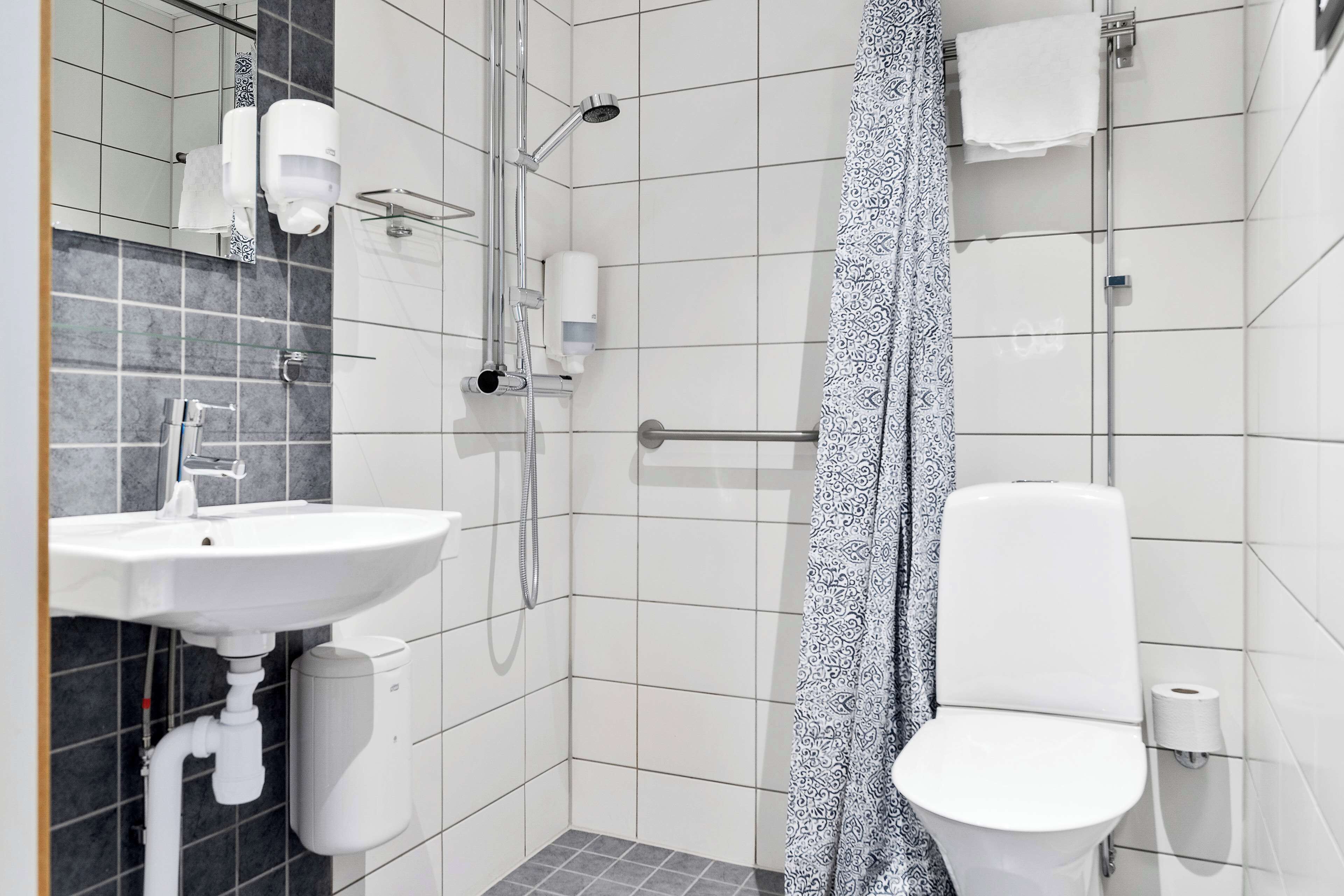 A modern bathroom with a white sink, toilet, and shower.