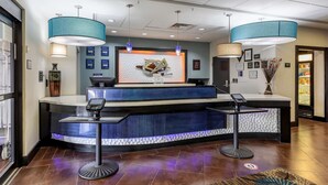 A reception area with a counter, two pendant lights, a decorative wall, and a floor with a patterned rug. - Best Western Plus North Odessa Inn & Suites (Odessa)
