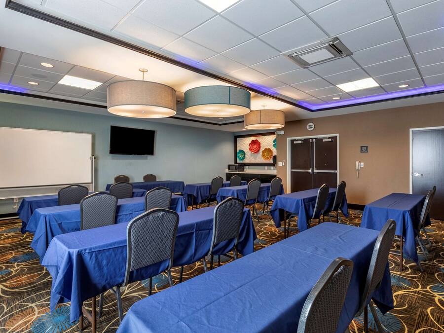 A conference room with tables and chairs, a whiteboard, and a television on the wall.