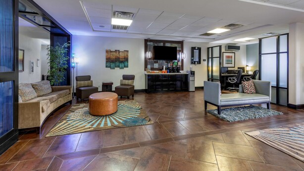 A spacious living area with a sofa, chairs, and a coffee table. There is a kitchen area with a counter and appliances in the background. - Best Western Plus North Odessa Inn & Suites (Odessa)