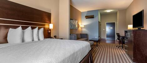 Habitación de hotel con una cama grande, un escritorio con una computadora, un televisor y un baño a la vista.