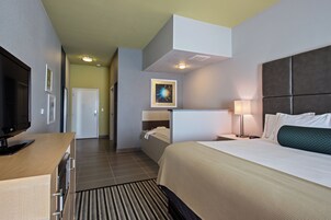 Habitación de hotel con cama, escritorio, televisión, baño y pasillo.