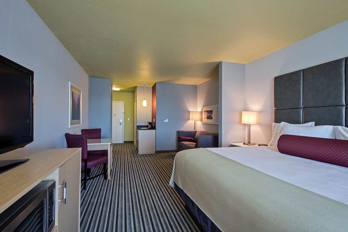 A hotel room with a bed, a desk, a chair, a TV, and a bathroom.
