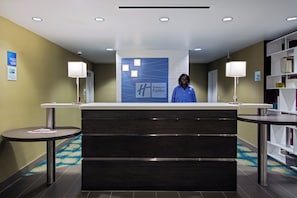 A hotel reception desk with a blue sign, two side tables, and a check-in/out sign. - Holiday Inn Express Hotel & Suites, Carlisle-Harrisburg Area by IHG (Carlisle)