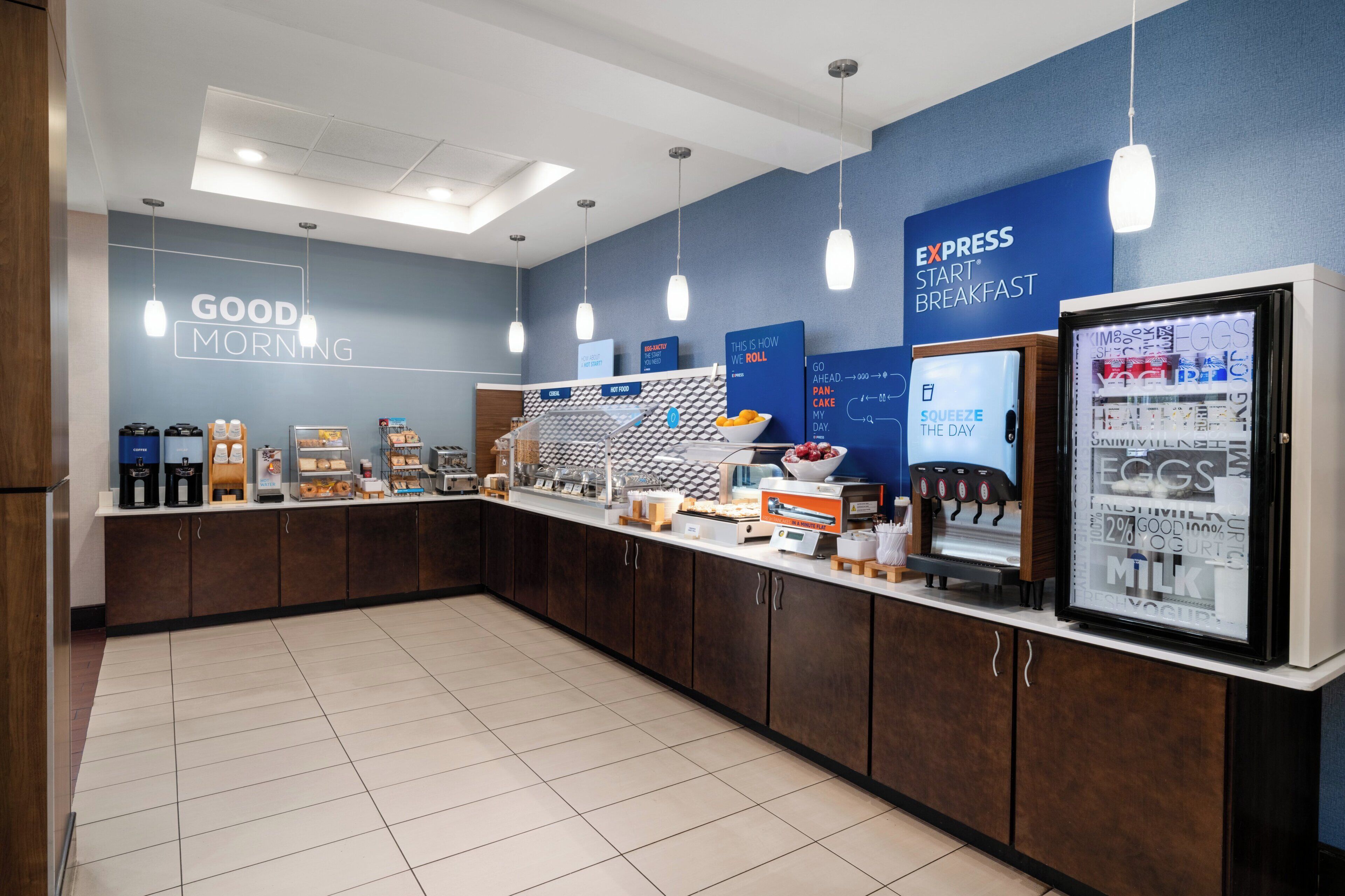 A breakfast area with a counter, coffee machines, and a refrigerator.