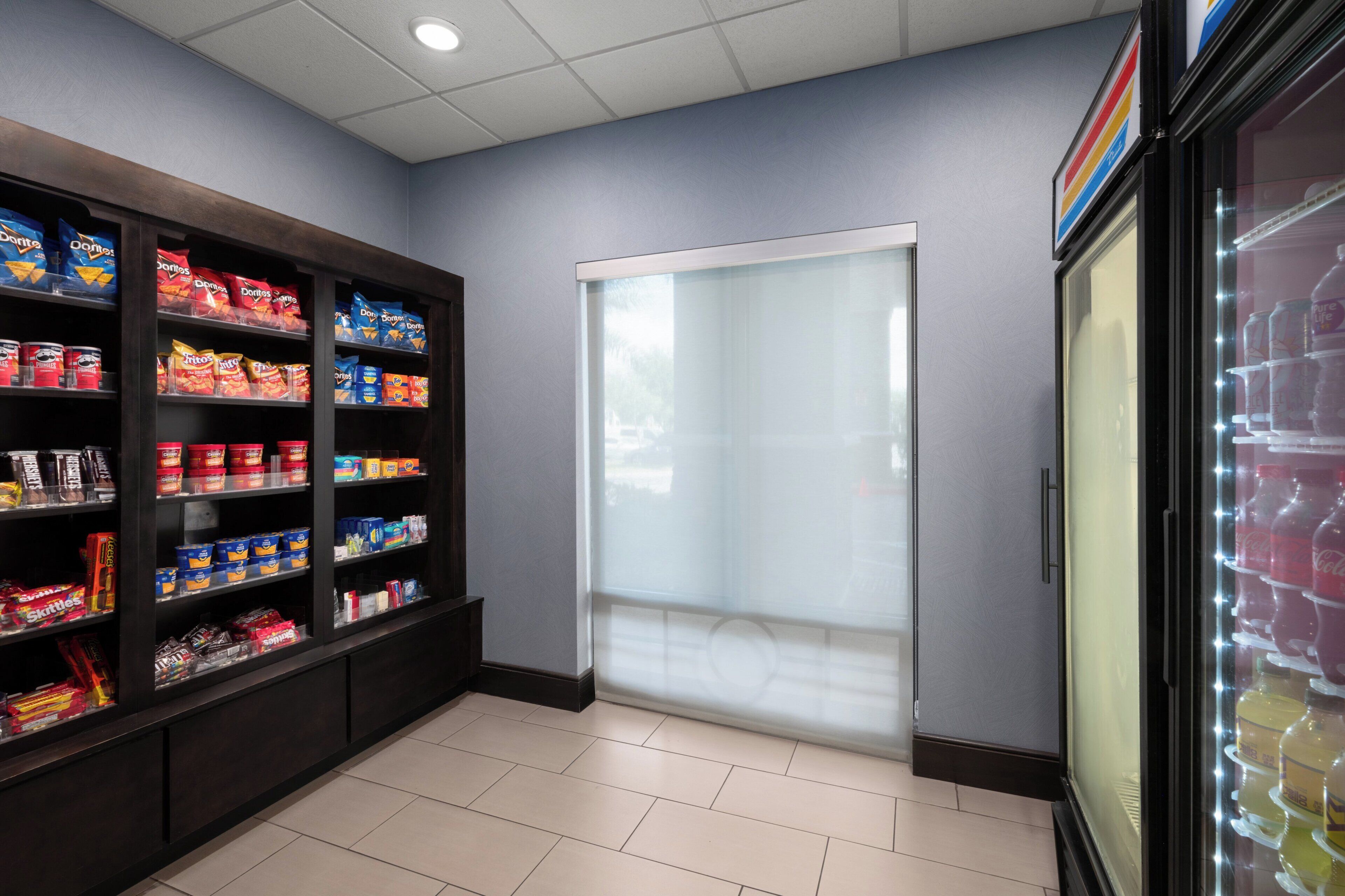 A snack display with various brands, a door with frosted glass, and a refrigerated beverage case.