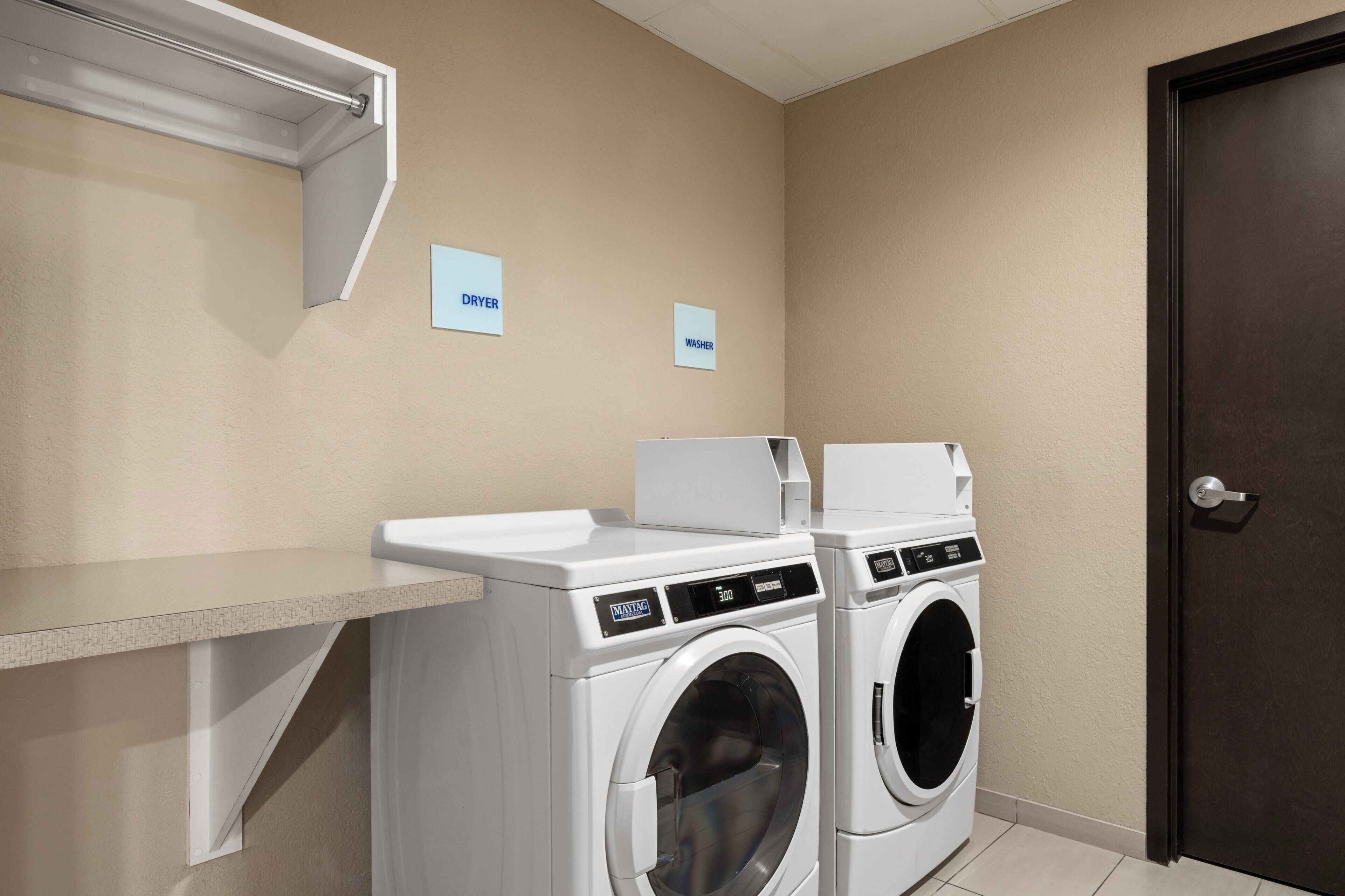 A laundry area with a washing machine and dryer, a towel rack, and a door.