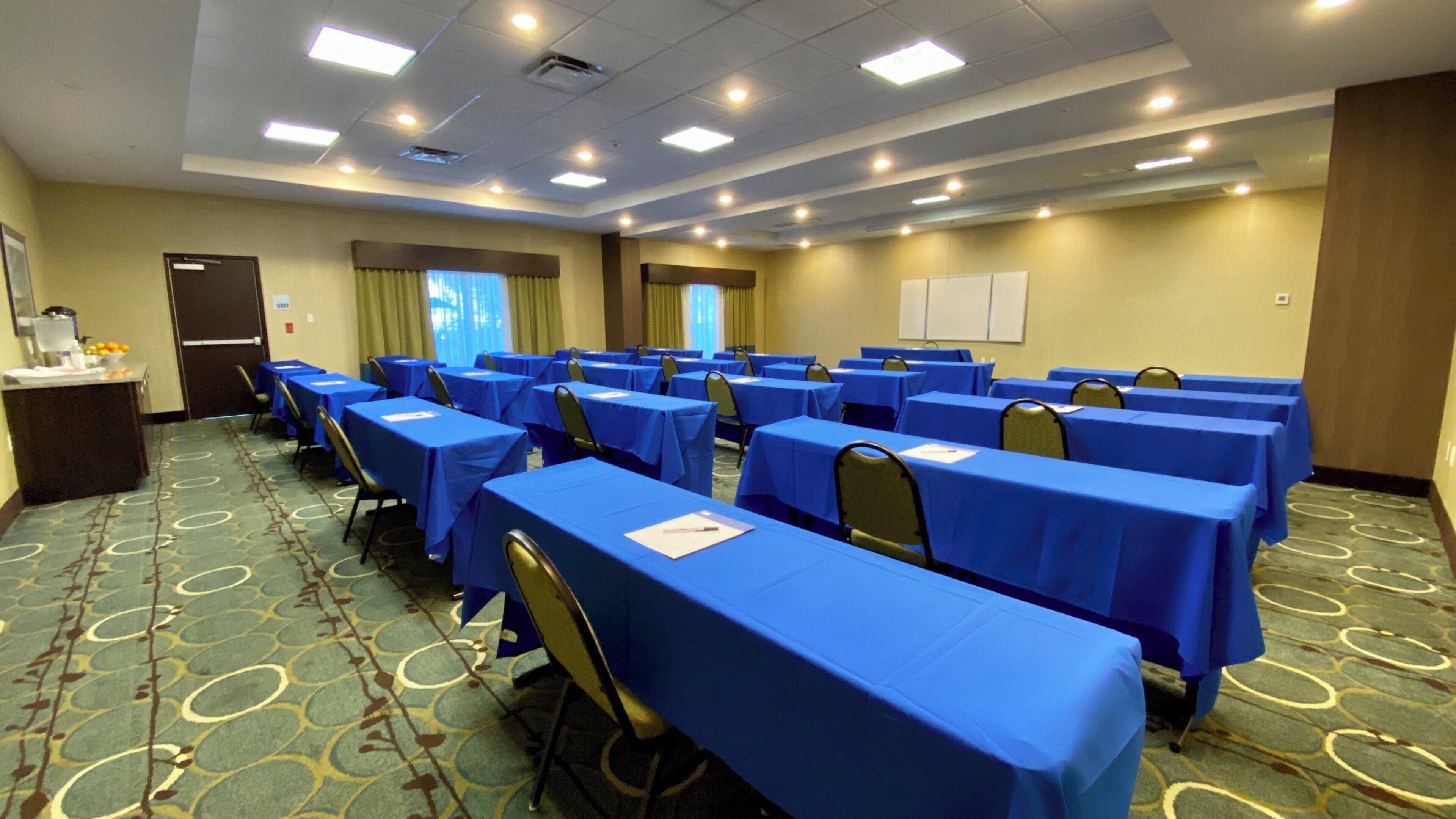 A conference room with multiple tables, chairs, and a podium.