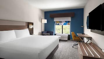 Habitación de hotel con una cama grande, un escritorio, una silla, un televisor y una ventana con vistas.