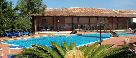 Una piscina al aire libre, sombrillas, tumbonas
