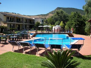 Una piscina al aire libre, sombrillas, tumbonas