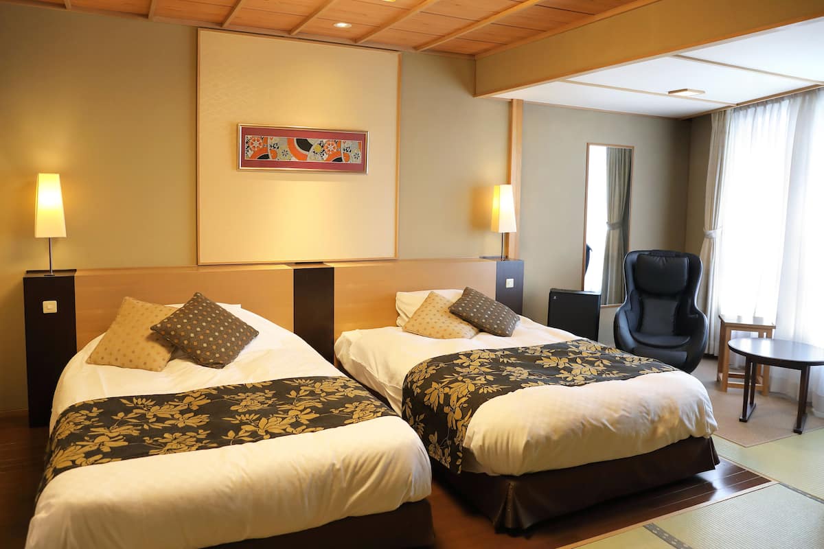 Une chambre d’hôtel avec deux lits, une chaise, une petite table et un tableau au mur.
