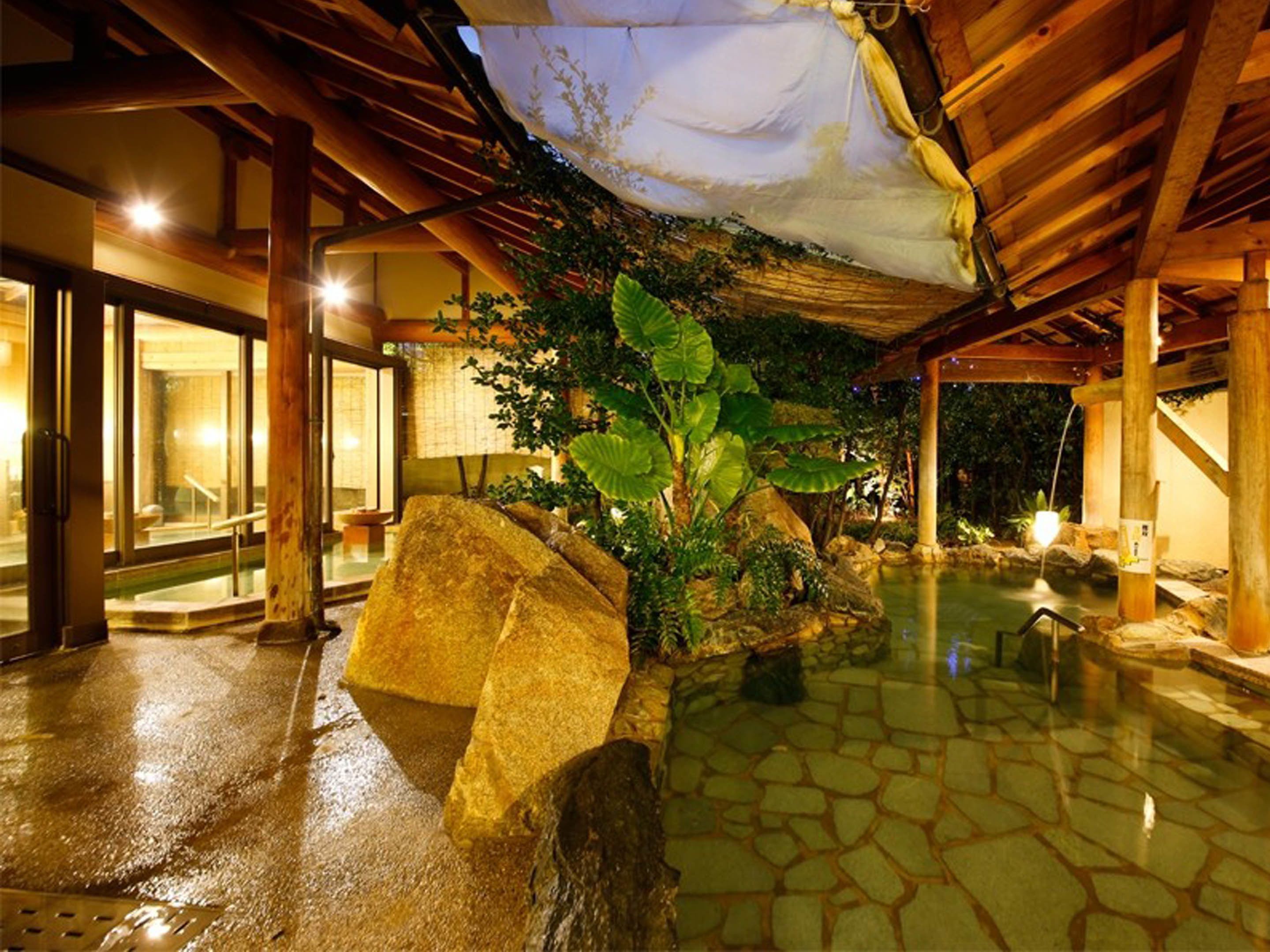 A spa area with a stone floor, large rocks, and a water feature.