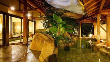 A spa area with a stone floor, large rocks, and a water feature.