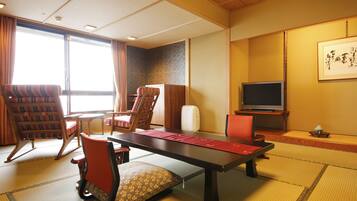 Une pièce de style japonais traditionnel, avec un sol recouvert de tatamis, une table basse et différents types de sièges, notamment un canapé et des fauteuils.