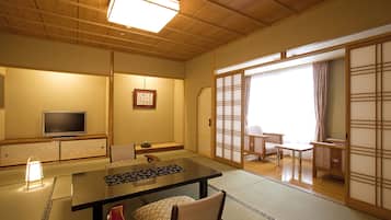 A traditional Japanese room with tatami flooring, a low table, a television, and sliding doors.