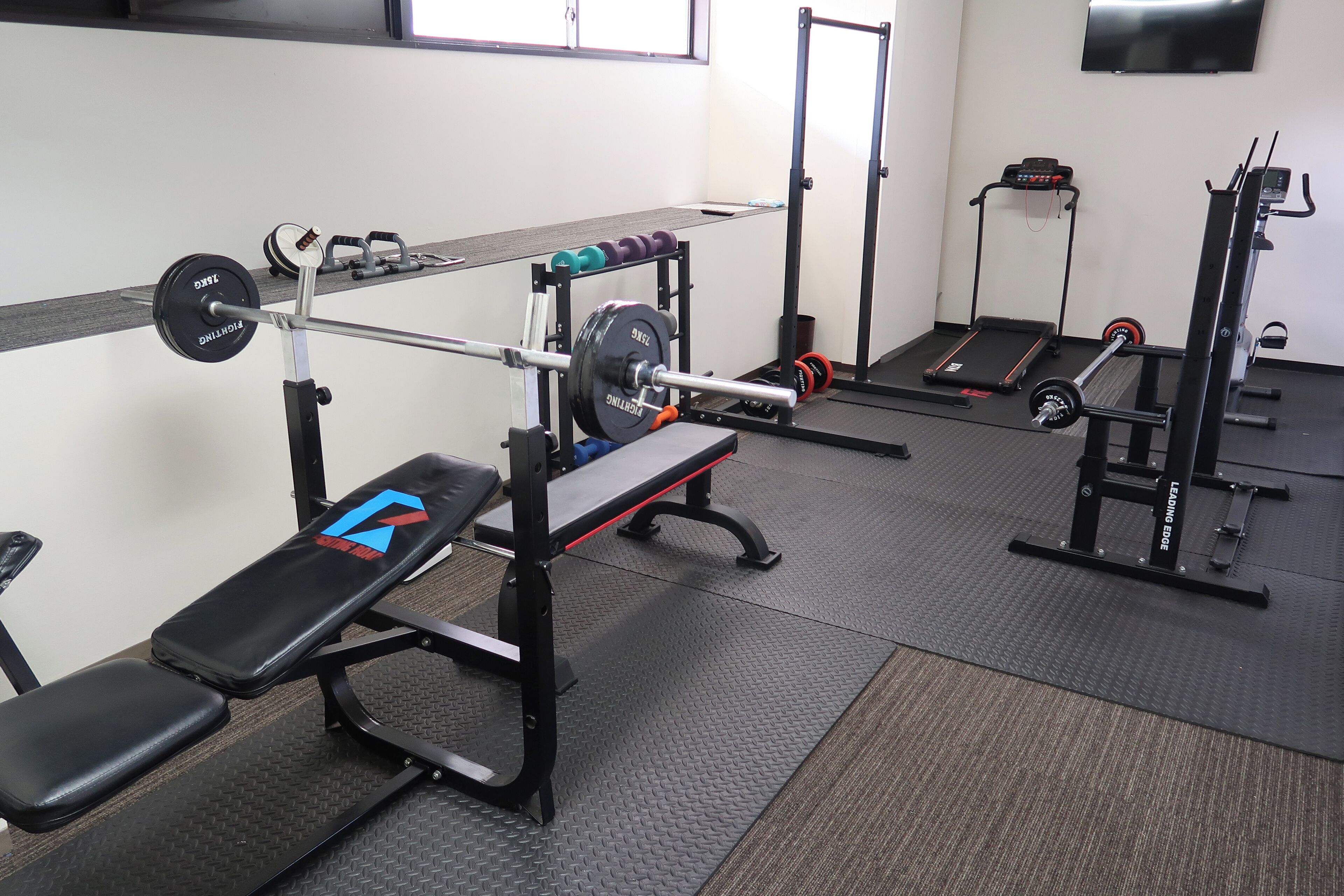 A gym with weightlifting equipment, treadmills, and benches.