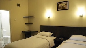 Habitación de hotel con dos camas, una mesita de noche, una estantería y un cuadro.