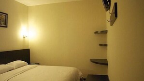 Una habitación de hotel con una cama, mesitas de noche y un estante en la pared.