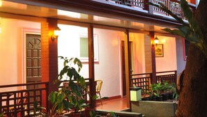 A two-story building with a balcony, potted plants, and a stone pathway. - Lola Itang Pension (Puerto Princesa)