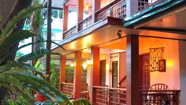 A two-story building with a balcony, potted plants, and a staircase. - Lola Itang Pension (Puerto Princesa)