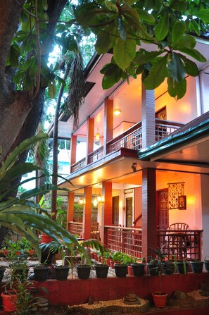 A two-story building with a balcony, potted plants, and a staircase.