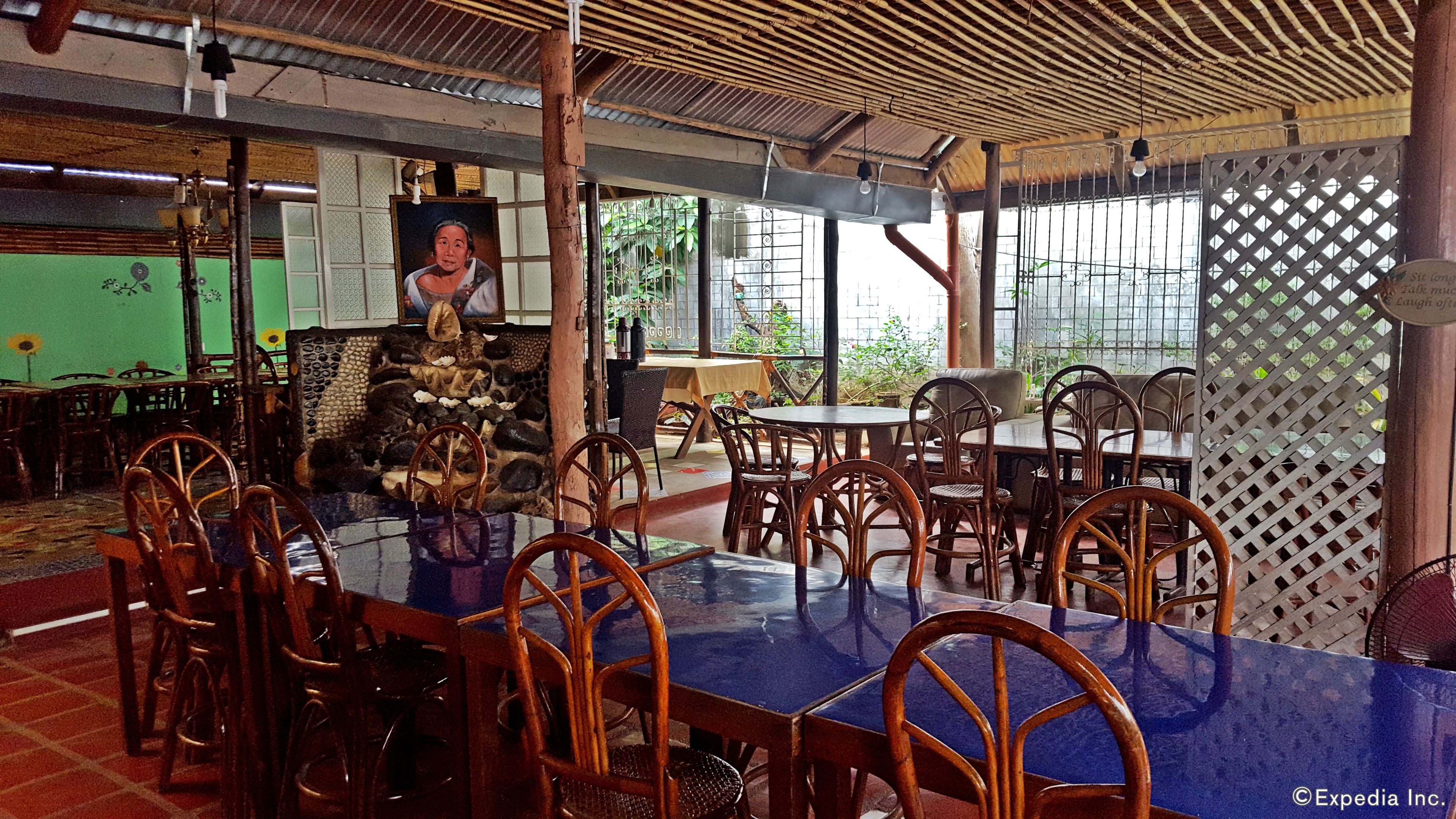 A restaurant with bamboo ceiling, stone wall, and wooden chairs.