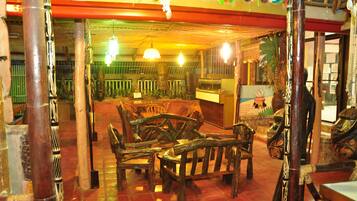 Un interior de madera tradicional con una zona de estar central y un techo decorativo.