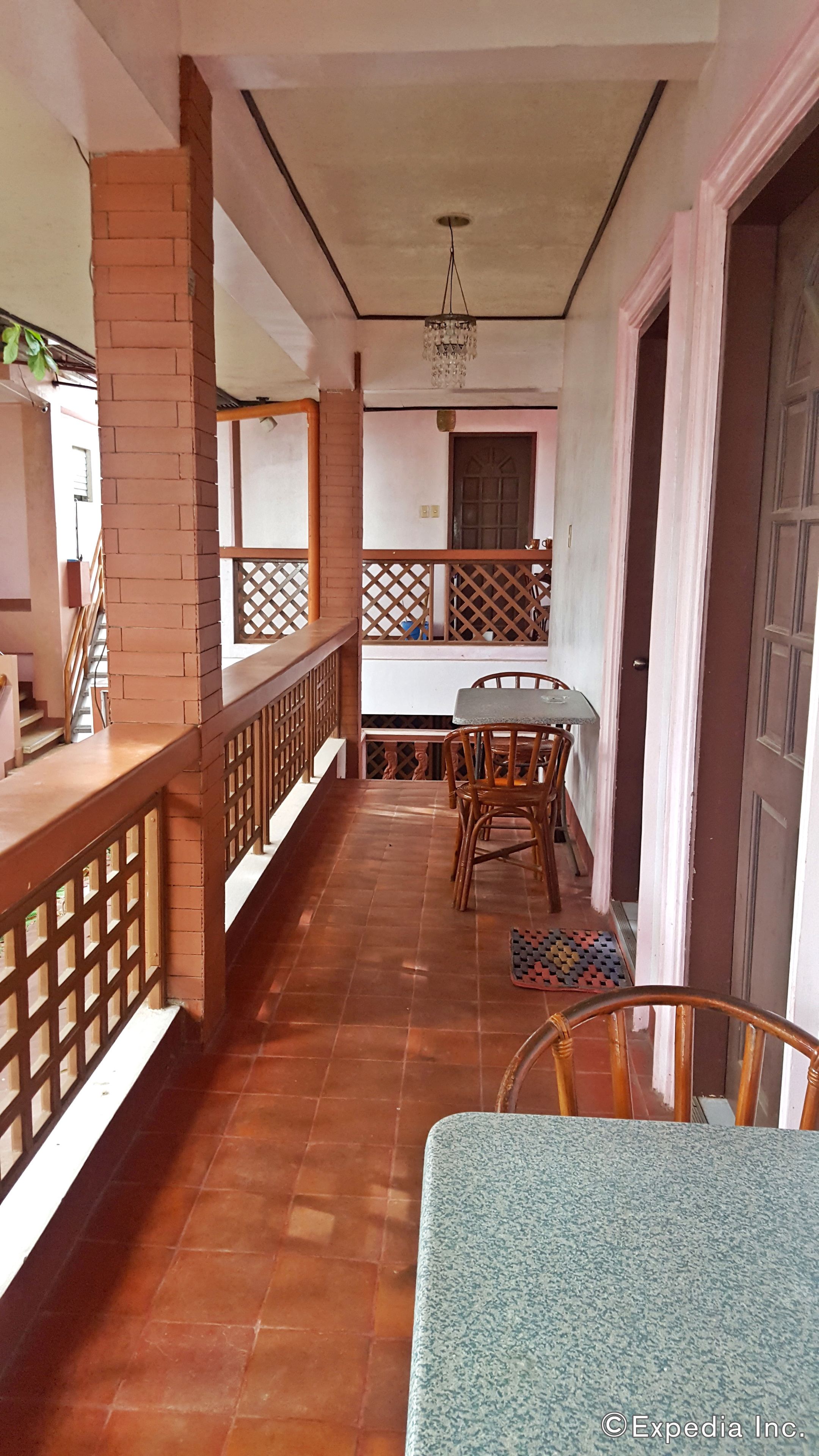 A balcony with a wooden railing, a table with chairs, and a chandelier.