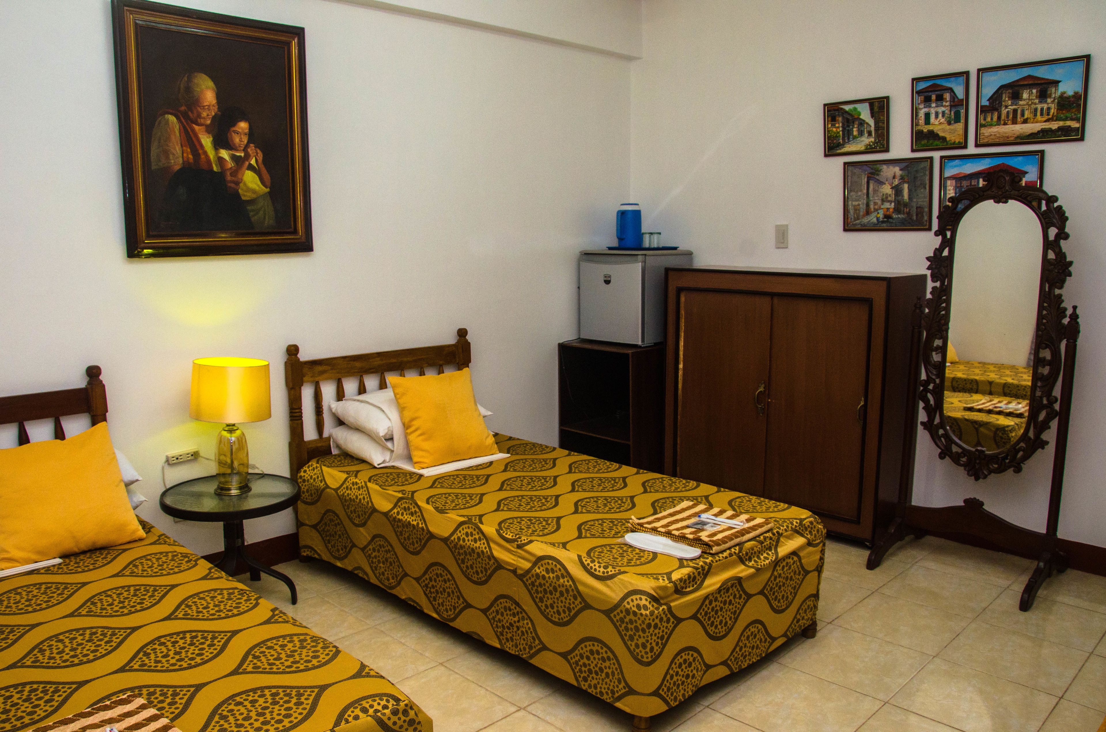 Una habitación de hotel con dos camas, un escritorio, un espejo y un armario.