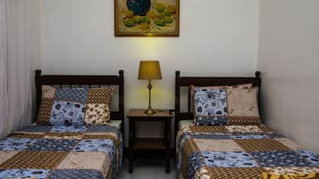A bedroom with two beds, a nightstand with a lamp, and a painting on the wall.
