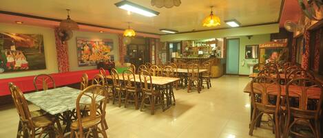 Un restaurante con varias mesas y sillas, una zona de bar y obras de arte en las paredes.
