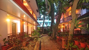 A courtyard with a stone pathway, potted plants, and buildings with balconies. - Lola Itang Pension (Puerto Princesa)