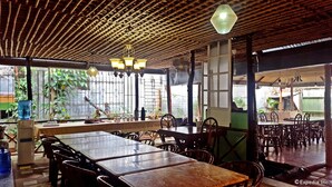 A restaurant with wooden tables and chairs, a bamboo ceiling, and hanging lights. - Lola Itang Pension (Puerto Princesa)