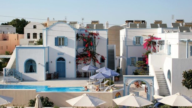 A hotel with a swimming pool, outdoor seating, and a staircase leading to the upper floors. - Preka Maria Hotel (Santorini)